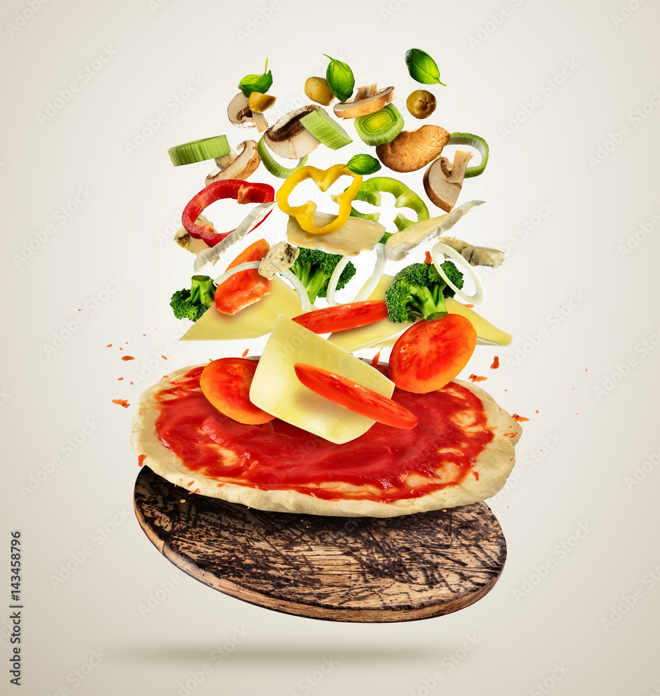 Flying ingredients with pizza dough, on creamy background