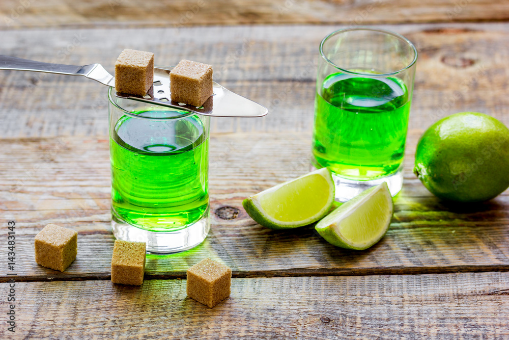 absinthe shots with lime slices and sugar on wooden table background