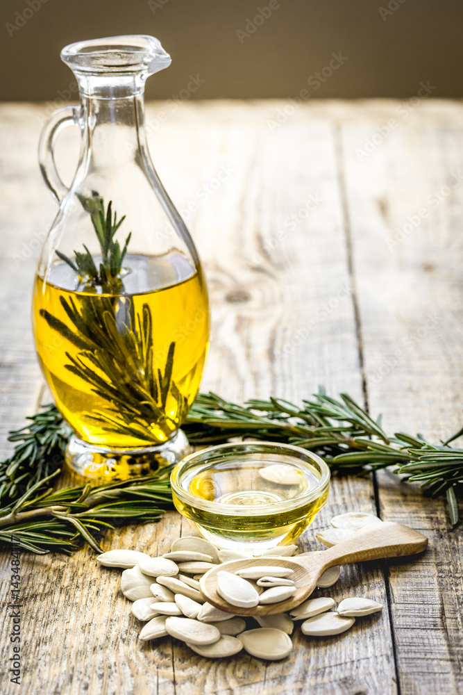 Bottle with pumpkin seeds oil and herbs on wooden background