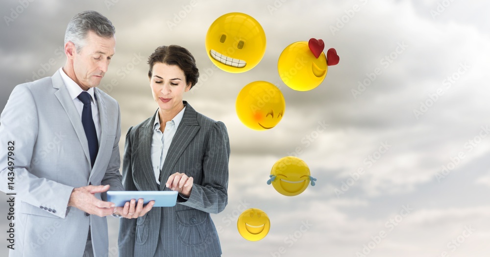 Business people with tablet against cloudy sky with emojis