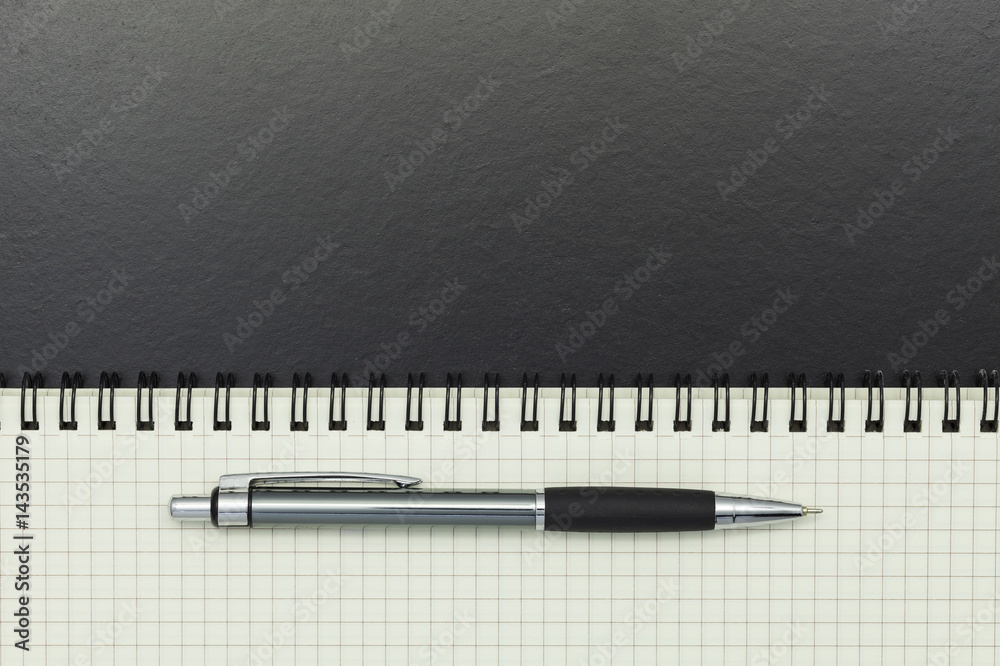 Pen with notebook on blackboard background.