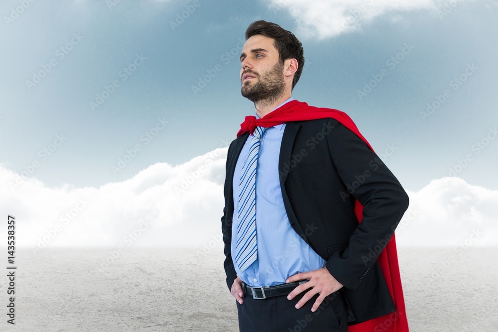 Businessman wearing cape while standing against sky