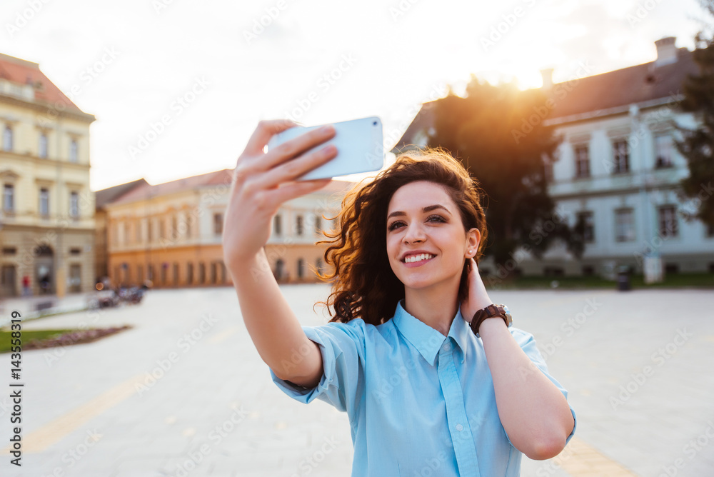 Cute young girl taking selfie in the city