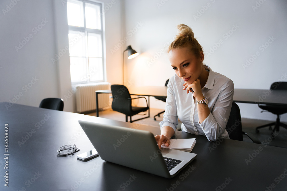 Blonde bussines woman spending time next to lap top in her office