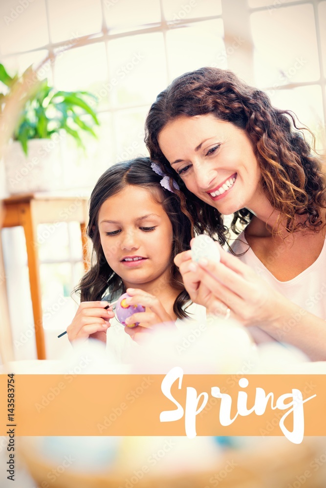 Happy mother and daughter painting Easter egg