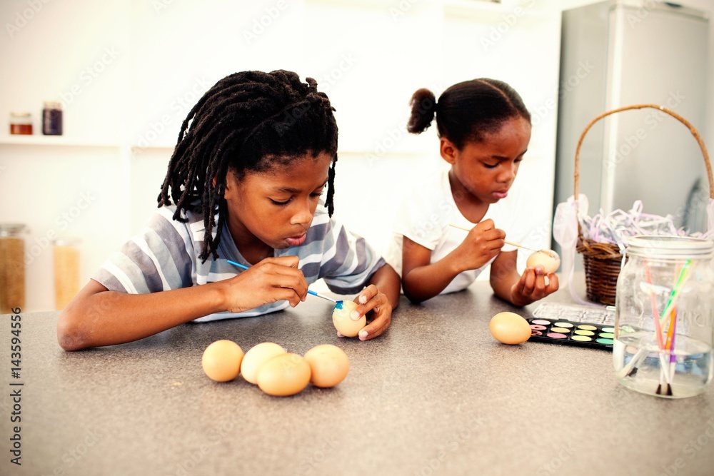 Concentrated siblings painting eggs 