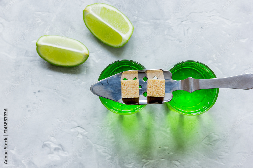 absinthe with sugar cubes in spoon on stone background top view