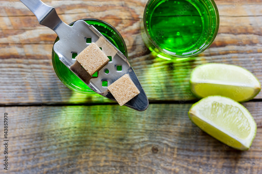 absinthe with sugar cubes in spoon on wooden background top view