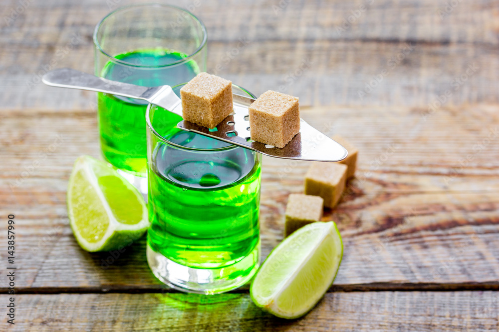 absinthe shots with lime slices and sugar on wooden table background