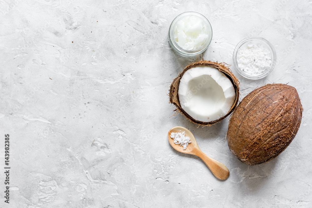 fresh coconut with cosmetic oil in jar on gray background top view