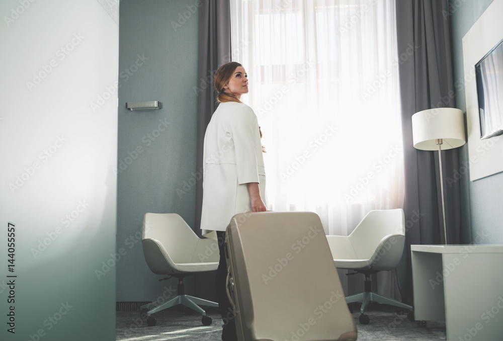 Woman pulling suitcase in modern hotel room