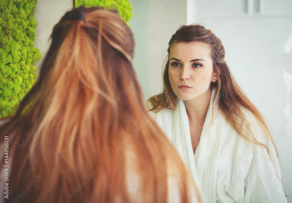 Pretty woman looking at mirror in modern bathroom