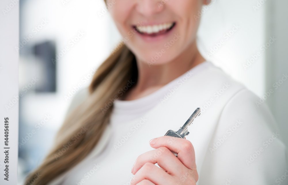 Happy woman holding house key of her new apartment