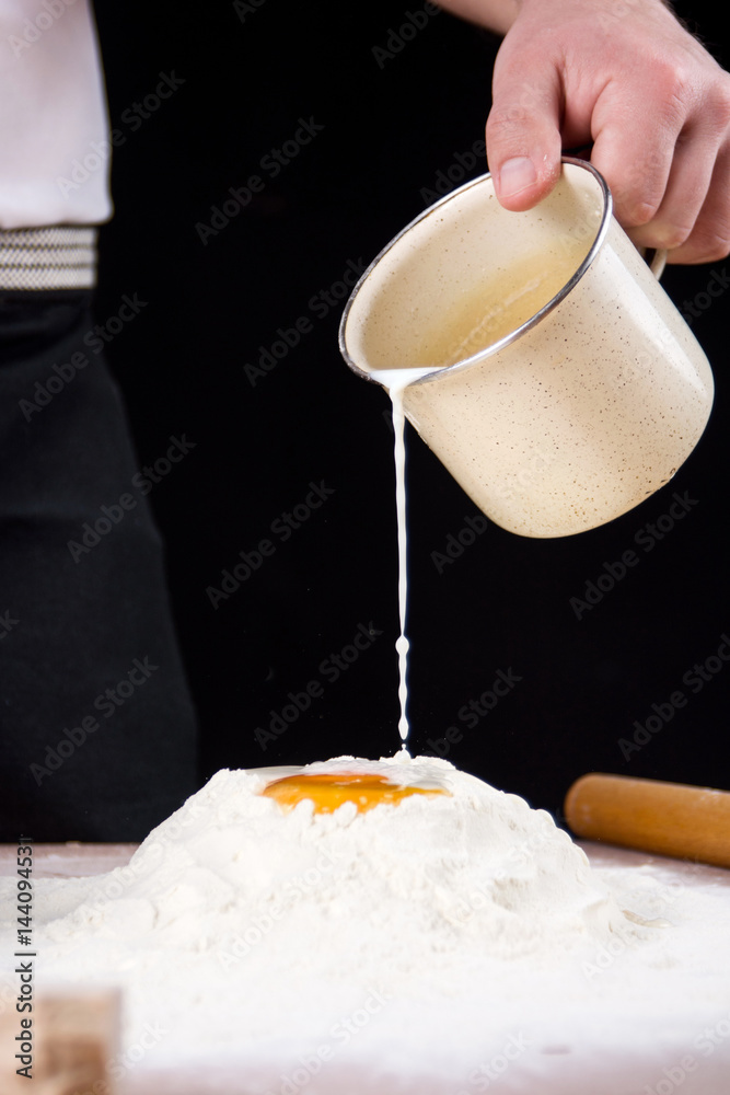 Man pouring milk and yeast on flour