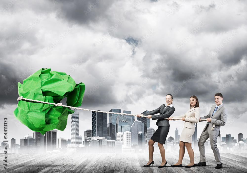 Young business people outdoors and huge paper ball as symbol of creativity