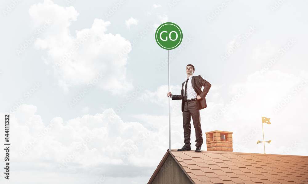 Businessman in suit on house top with ecology concept signboard.