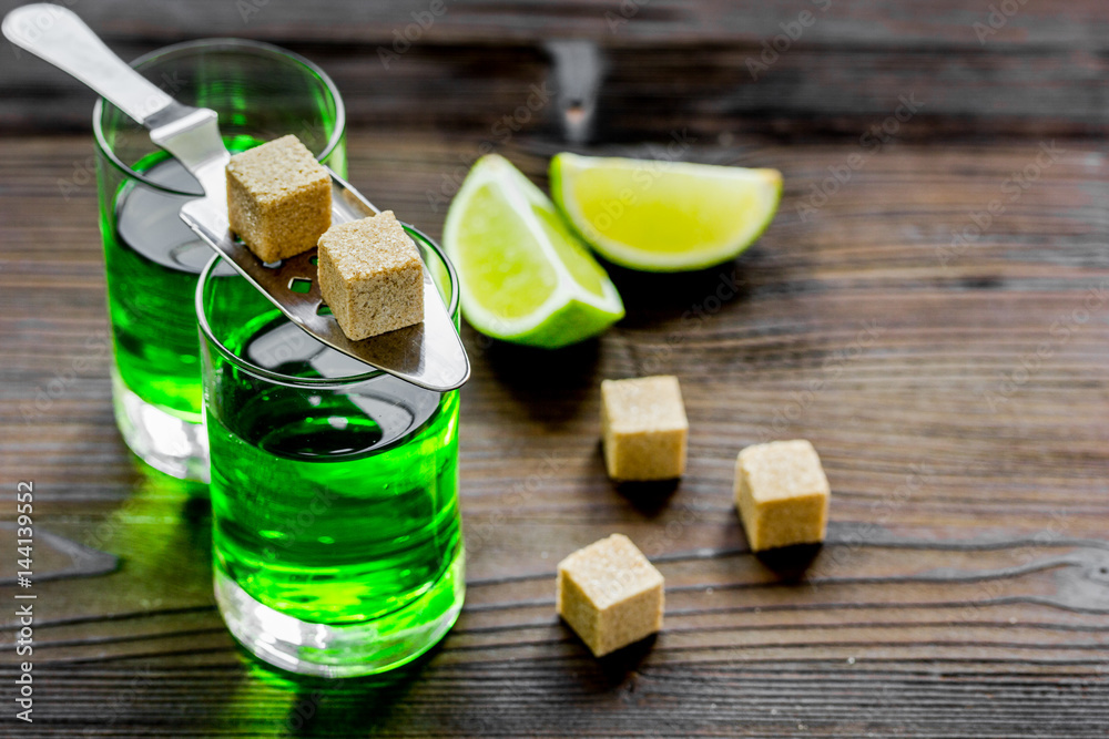 absinthe shots with lime slices and sugar on wooden table background