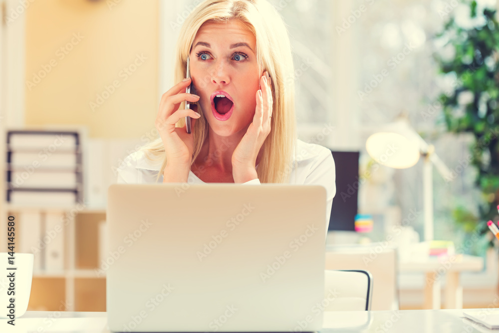 Surprised young woman talking on the phone