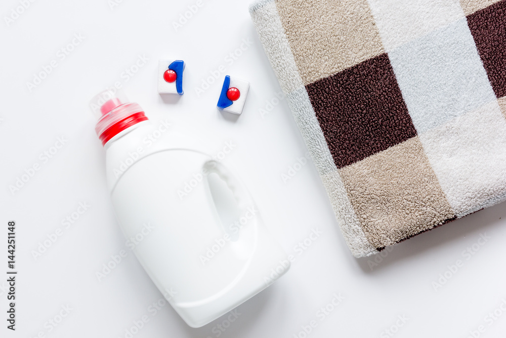 Pile of pastel towels with detergent white background top view