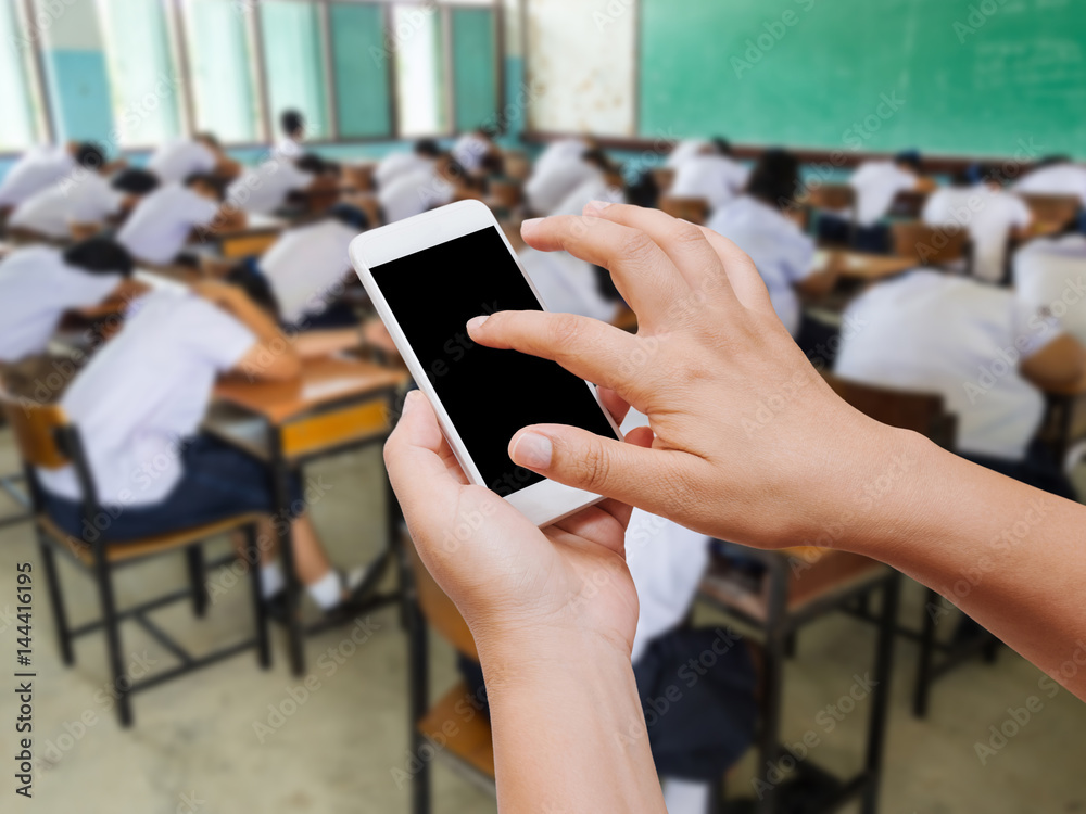 Woman hand hold and touch screen smart phone on students sleeping in class background.