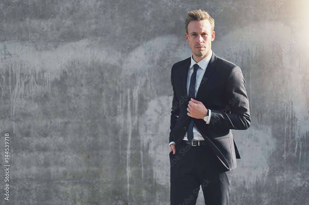 Adult businessman standing at the gray wall