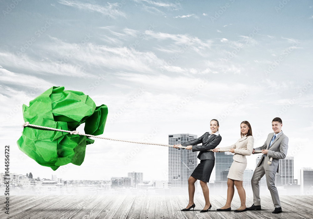 Young business people outdoors and huge paper ball as symbol of creativity