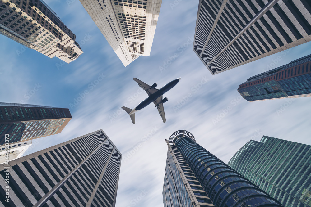 Airplane flying over city business buildings, high-rise skyscrapers