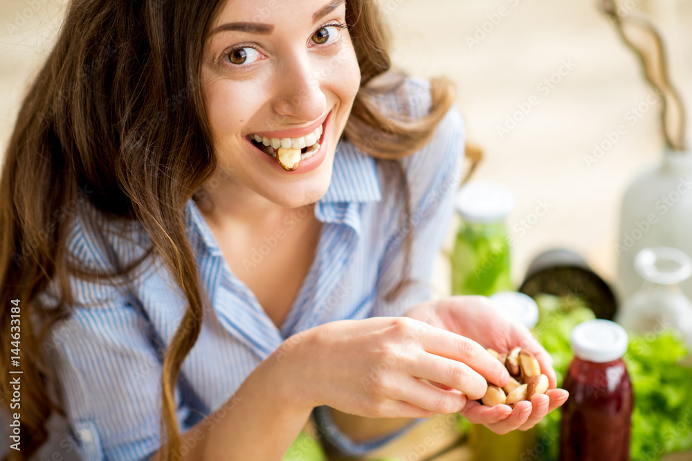 Closeup view from above of a woman eating brasil nuts with healthy food on the background