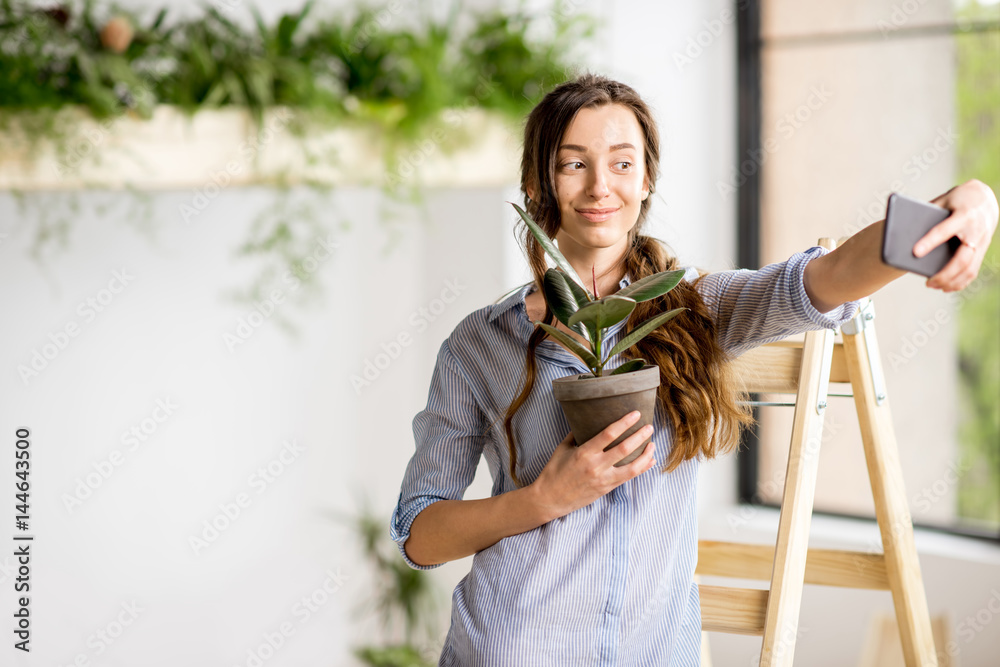 女人拿着花盆站在家里的梯子上自拍