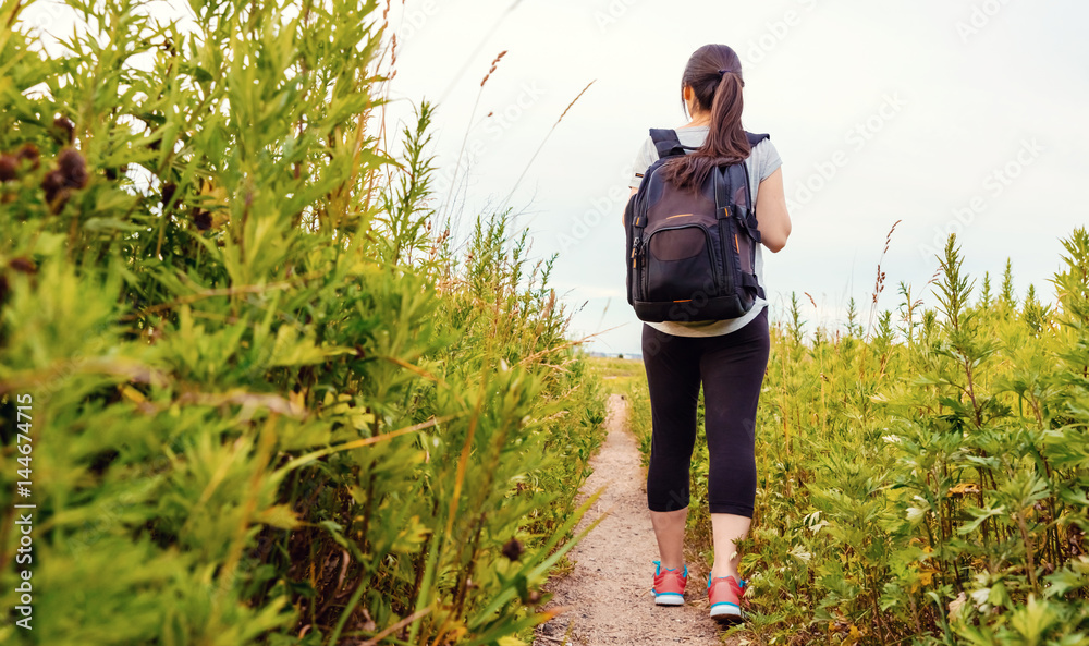 Woman with a backpack walking down a trail