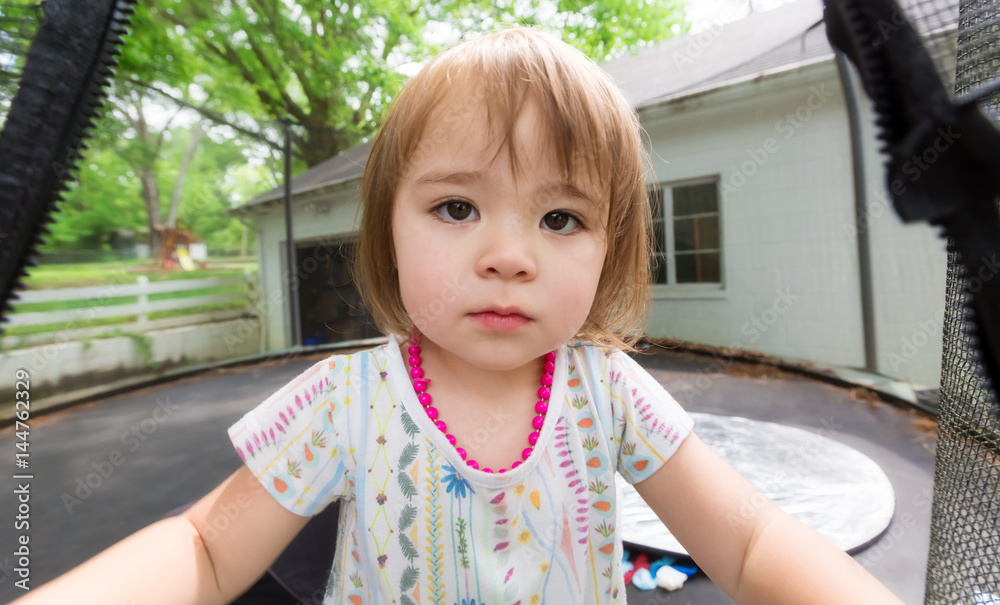 Toddler girl playing on her trampoline