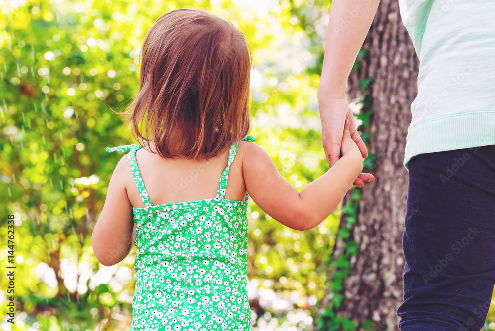 Toddler girl holding hands with her mother