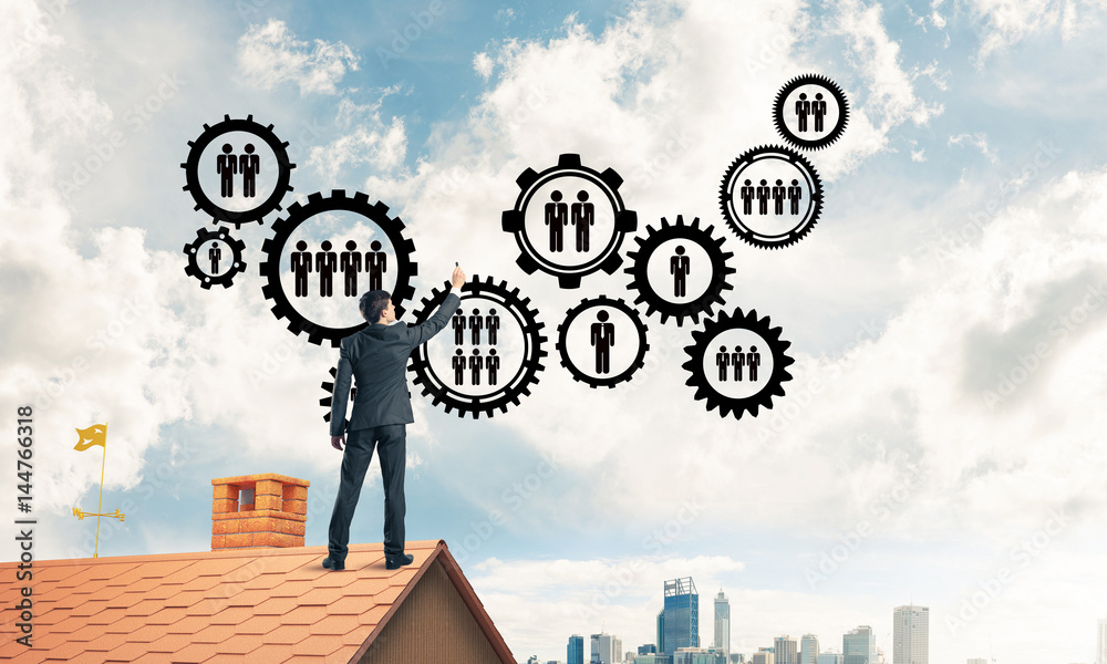 Businessman on house roof presenting teamwork and connection con