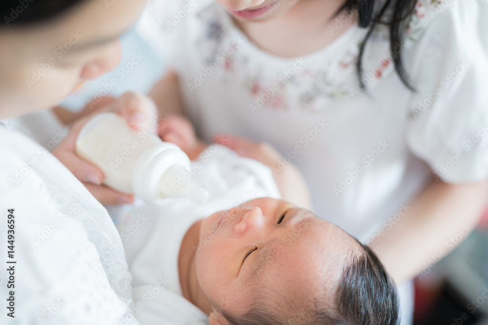 姐姐和妈妈一起照顾亚洲新生儿