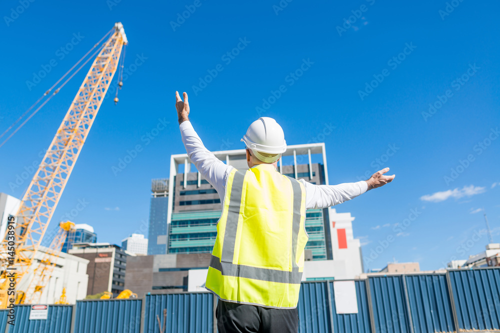 阳光明媚的日子里，戴着眼镜的高级工头在建筑区工作