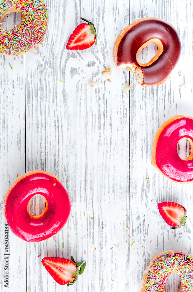 sweet colorful donuts with topping on wooden desk background top view mock-up