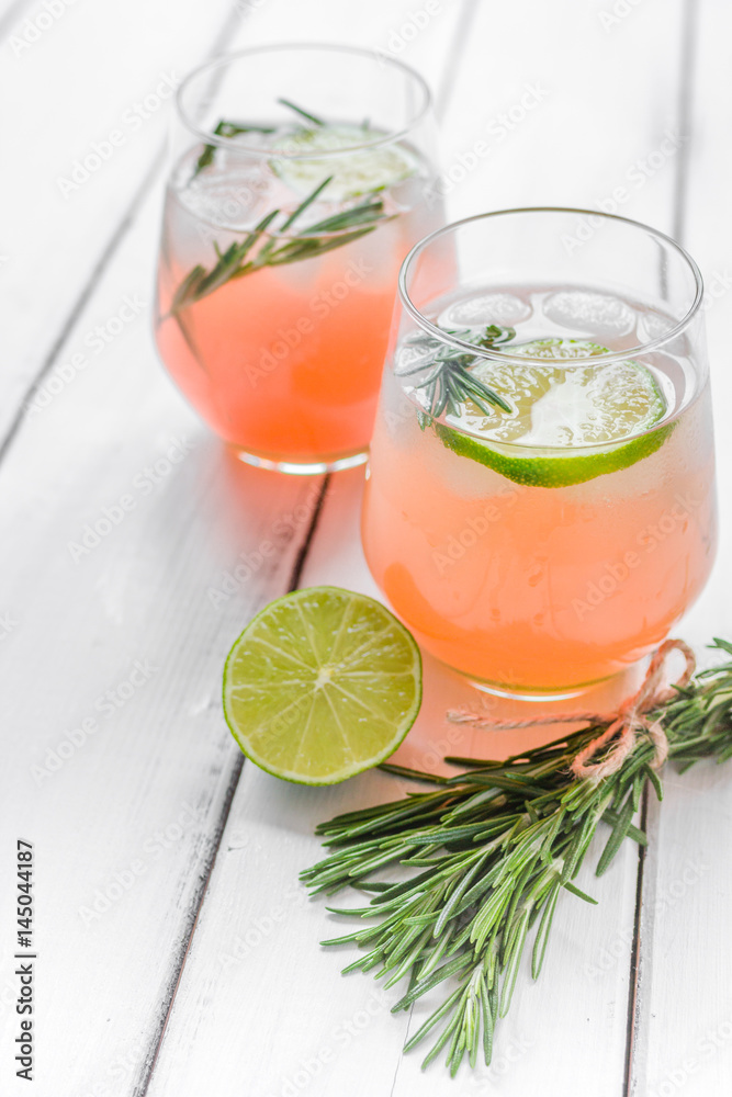 vegetable smoothie with lime and rosemary in glass on white table background