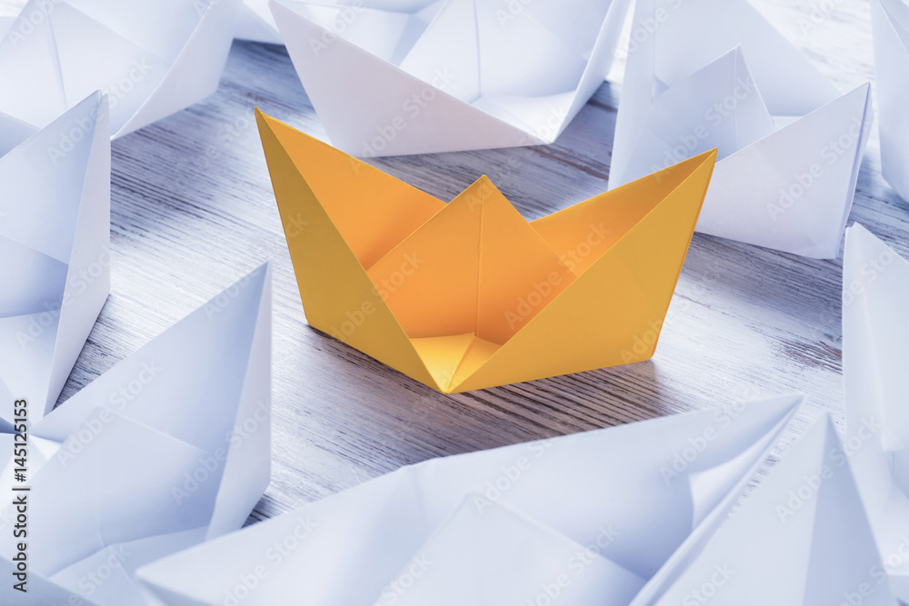 Business leadership concept with white and color paper boats on 