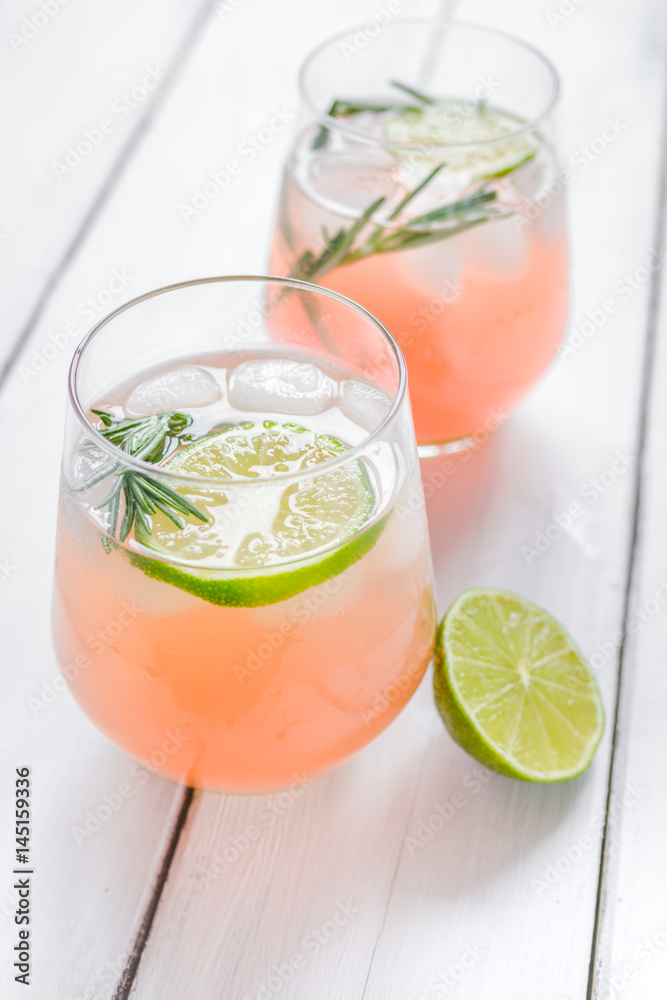 glass of fresh juice with lime and rosemary on wooden table background