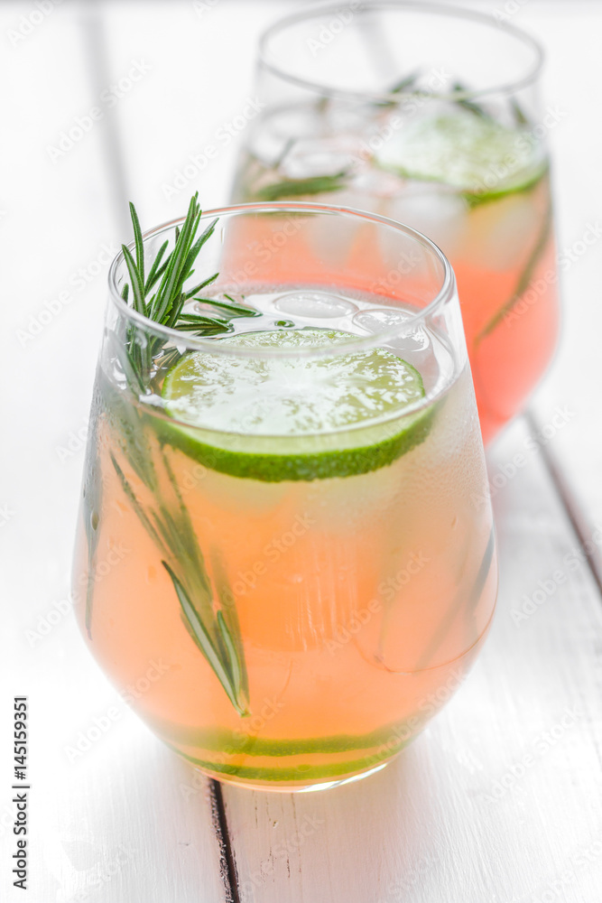 glass of fresh juice with lime and rosemary on wooden table background