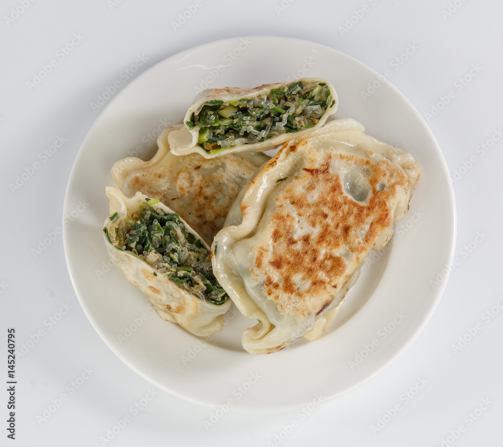 pan-fried leek dumplings on a plate isolated on white background
