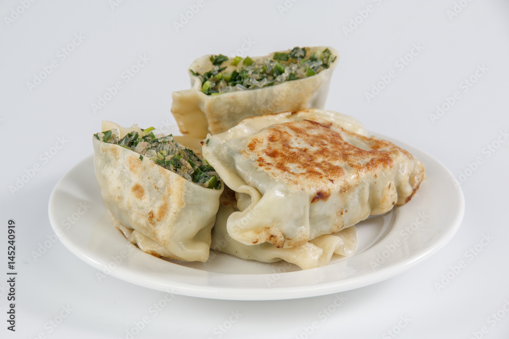 pan-fried leek dumplings on a plate isolated on white background
