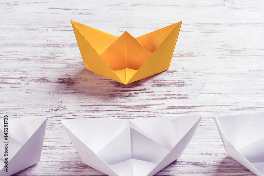 Business leadership concept with white and color paper boats on 