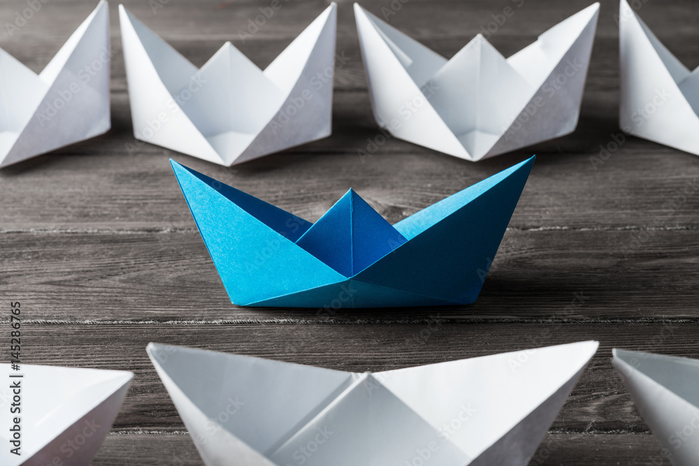 Business leadership concept with white and color paper boats on 