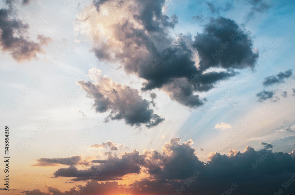 Golden light shining through the clouds in a colorful evening at sunset and blue sky