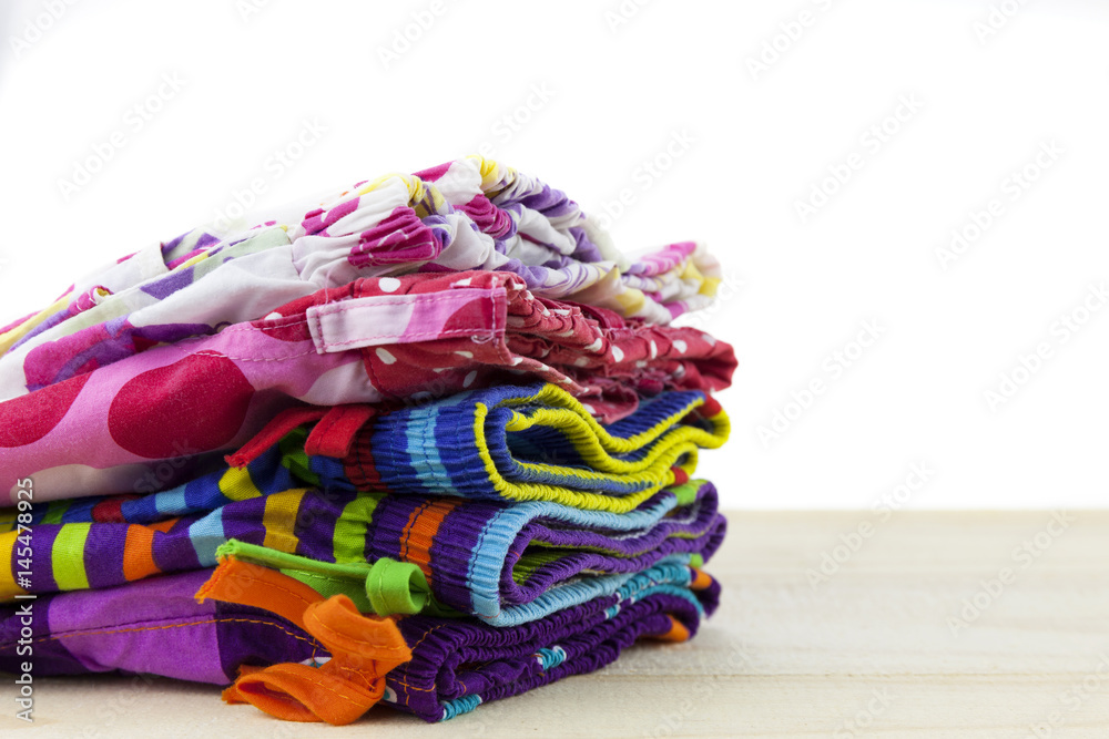 Pile of clothes colorful summer clothing on wood,white background.