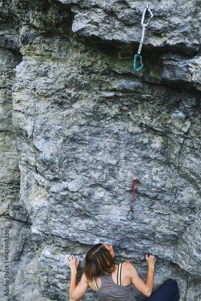 woman rock climber. rock climber climbs on a rocky wall. woman makes hard move