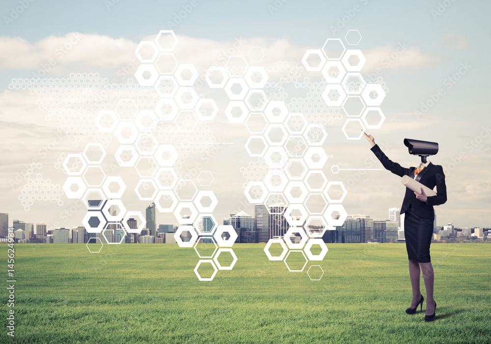 Camera headed woman standing on green grass against modern citys