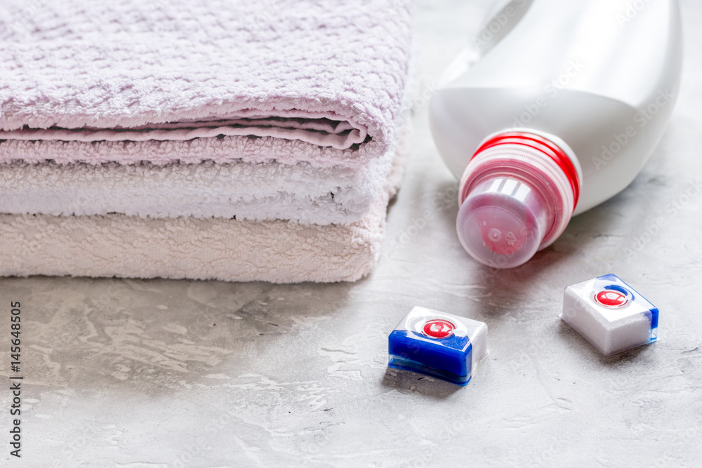 Plastic bottle with towel pile on light desk background