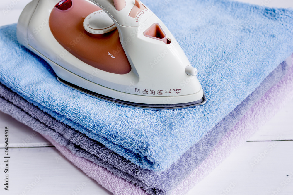 ironing pile of towels in laundry on light desk background